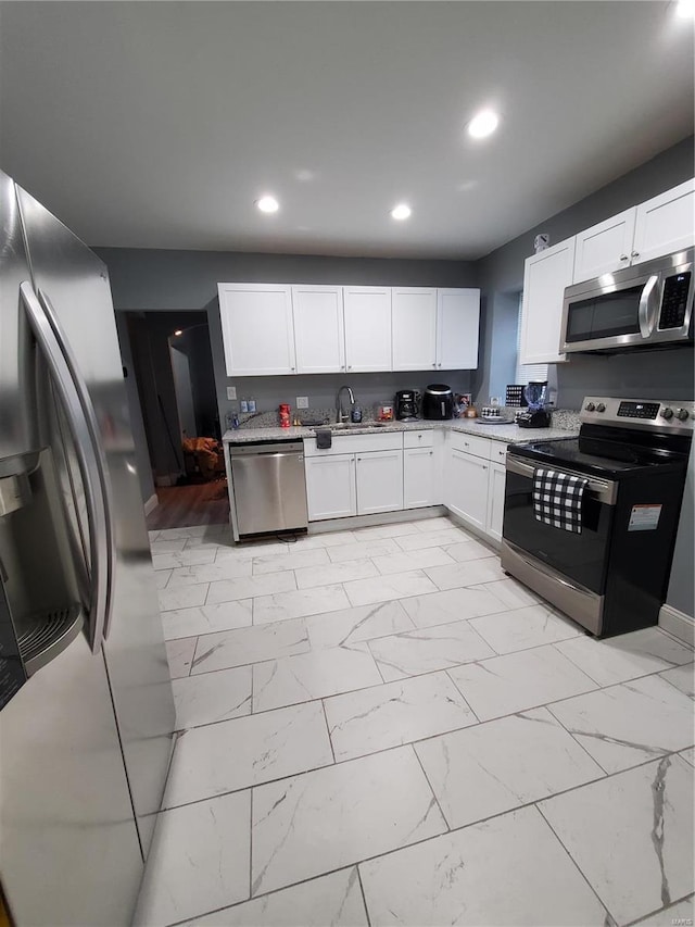 kitchen featuring white cabinets, stainless steel appliances, and light tile floors