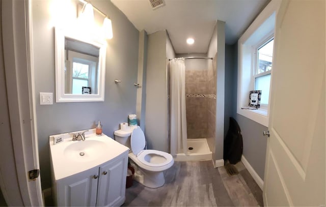 bathroom with hardwood / wood-style floors, a shower with shower curtain, toilet, and a healthy amount of sunlight