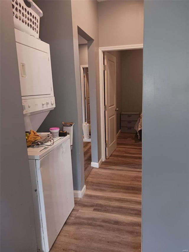 corridor featuring hardwood / wood-style flooring and stacked washer and clothes dryer