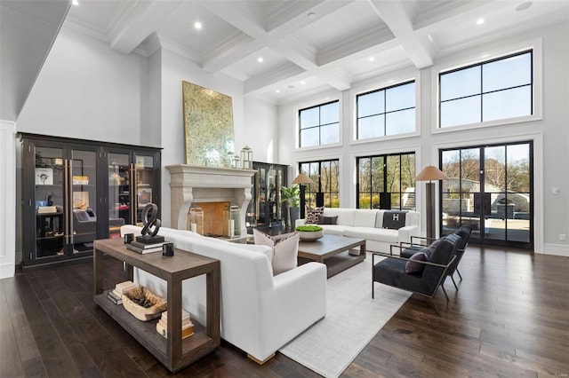 living room with dark wood-type flooring, beam ceiling, a high end fireplace, and a towering ceiling