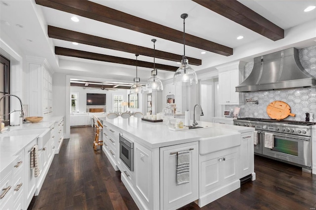 kitchen with dark hardwood / wood-style flooring, appliances with stainless steel finishes, sink, white cabinetry, and wall chimney range hood