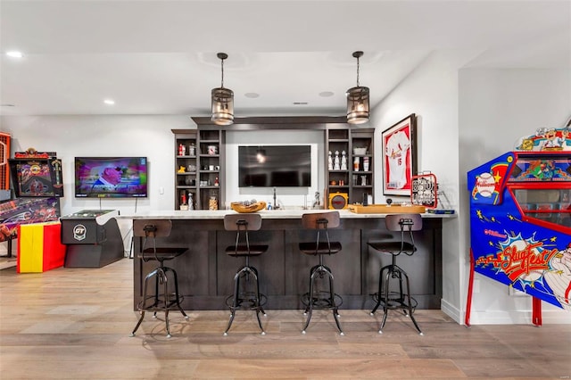 bar featuring decorative light fixtures and light hardwood / wood-style floors