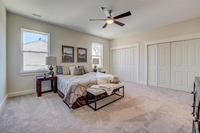 carpeted bedroom with two closets and ceiling fan