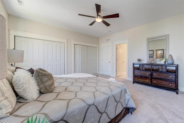 carpeted bedroom featuring multiple closets and ceiling fan