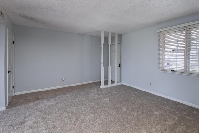 spare room featuring dark carpet and a textured ceiling