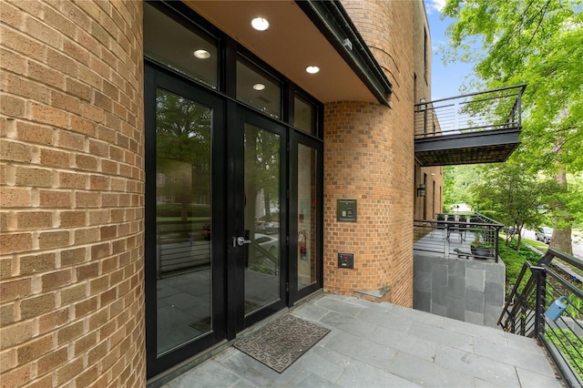 view of exterior entry with a balcony and french doors