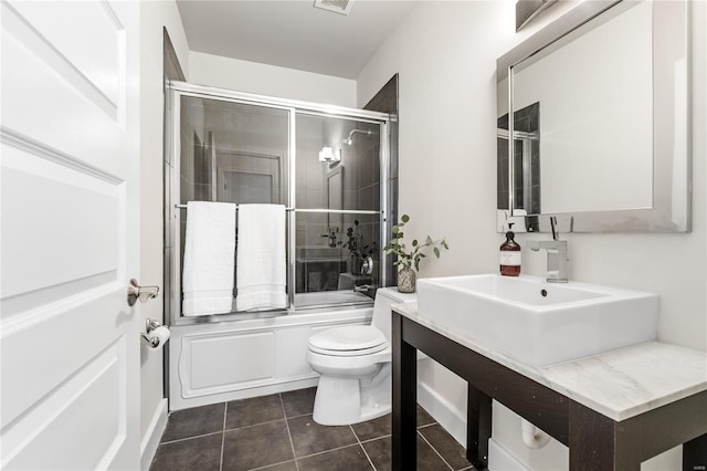 bathroom featuring tile patterned flooring, toilet, and enclosed tub / shower combo