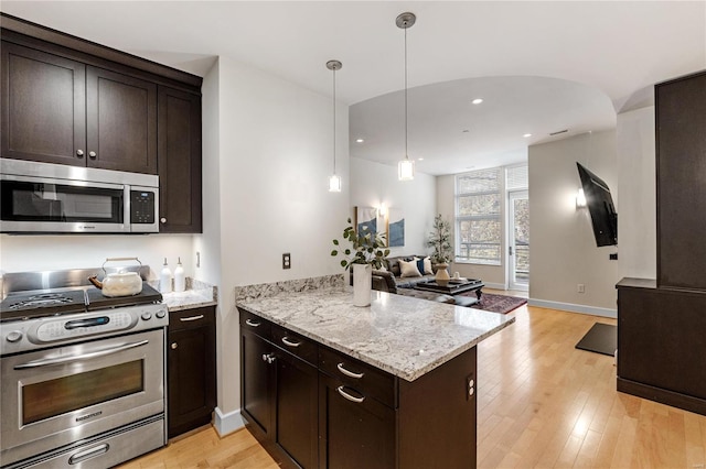 kitchen with light hardwood / wood-style floors, kitchen peninsula, hanging light fixtures, and appliances with stainless steel finishes