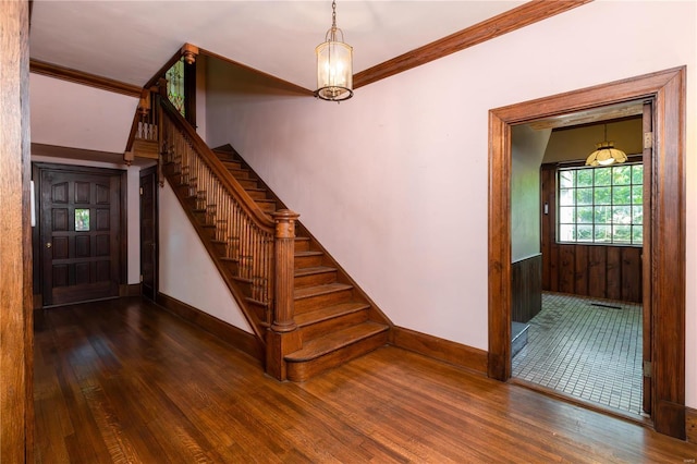 staircase featuring crown molding, a notable chandelier, and hardwood / wood-style flooring