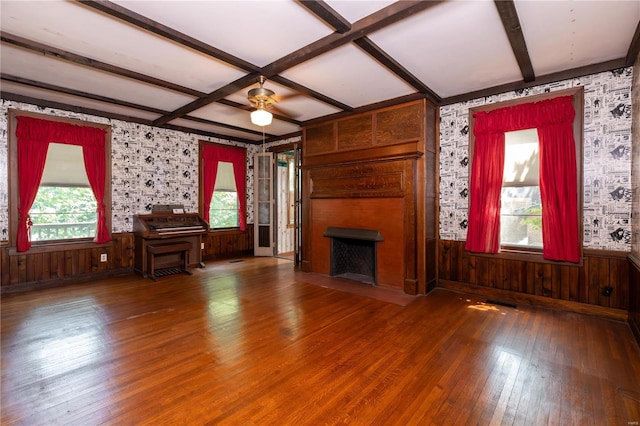 unfurnished living room featuring beam ceiling, hardwood / wood-style flooring, coffered ceiling, and wood walls