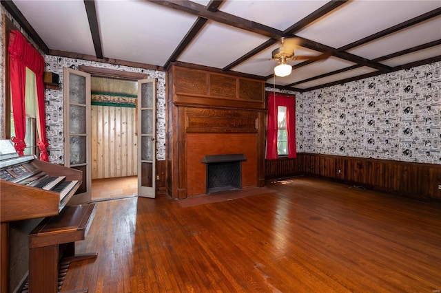 unfurnished living room featuring ceiling fan, a fireplace, beamed ceiling, and wood-type flooring