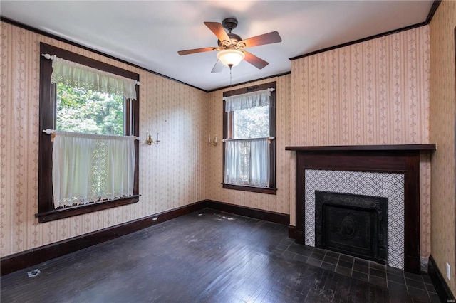 unfurnished living room featuring crown molding, ceiling fan, dark hardwood / wood-style floors, and a tiled fireplace