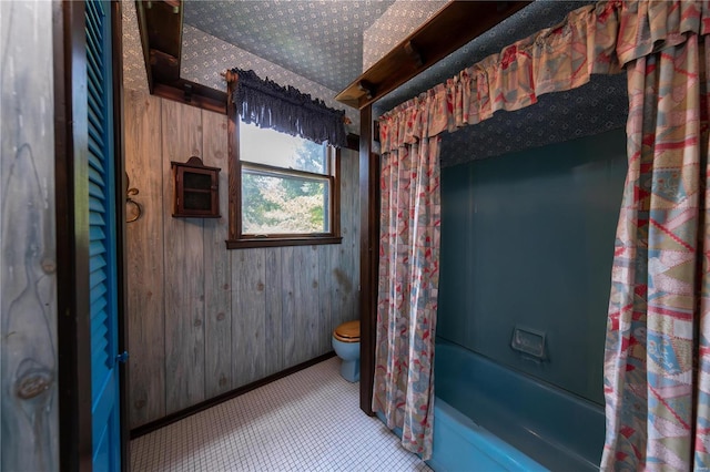 bathroom featuring shower / bath combination with curtain, wooden walls, and toilet