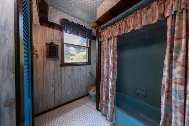 bathroom with toilet, shower / bathtub combination with curtain, and wood walls