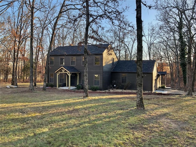 back of property with covered porch and a yard