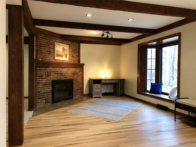 unfurnished living room featuring a brick fireplace, light hardwood / wood-style flooring, and beam ceiling