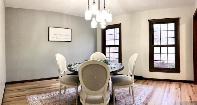 dining area featuring light wood-type flooring, plenty of natural light, and a notable chandelier