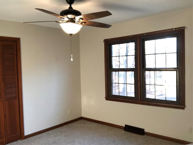 empty room with ceiling fan and light carpet