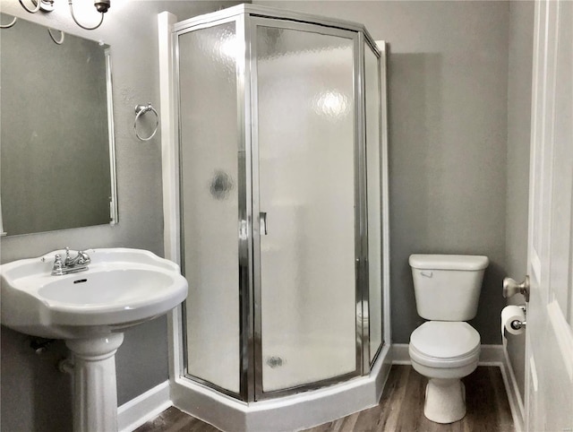 bathroom with toilet, wood-type flooring, sink, and a shower with door