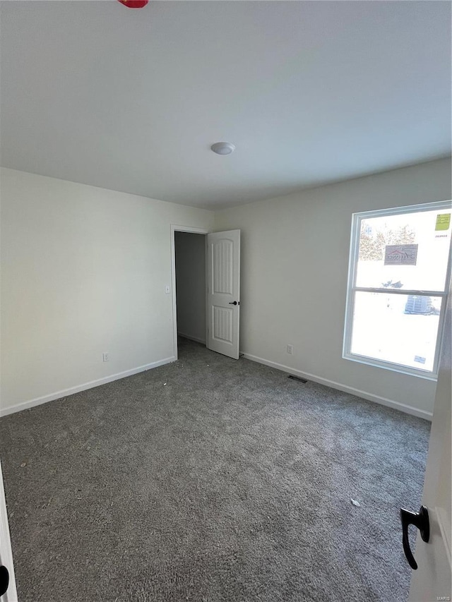 spare room featuring dark colored carpet