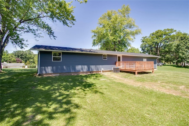 rear view of property with a lawn, a wooden deck, and central AC unit