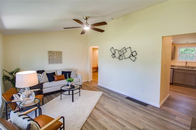 living room featuring ceiling fan, light hardwood / wood-style flooring, lofted ceiling, and sink