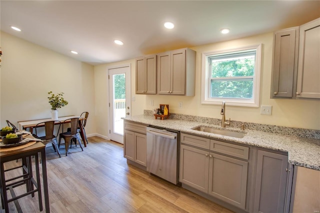 kitchen featuring gray cabinetry, light stone countertops, sink, light hardwood / wood-style flooring, and stainless steel dishwasher