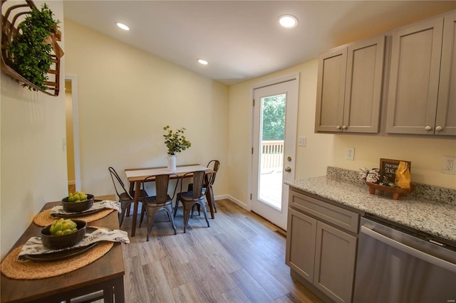 kitchen featuring gray cabinets, light hardwood / wood-style flooring, stainless steel dishwasher, and light stone counters