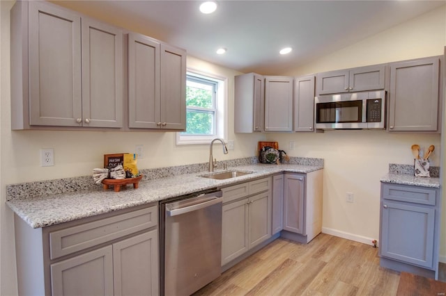 kitchen featuring gray cabinetry, stainless steel appliances, sink, light hardwood / wood-style floors, and lofted ceiling