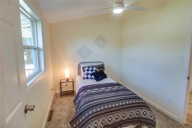 bedroom with multiple windows, ceiling fan, and light colored carpet