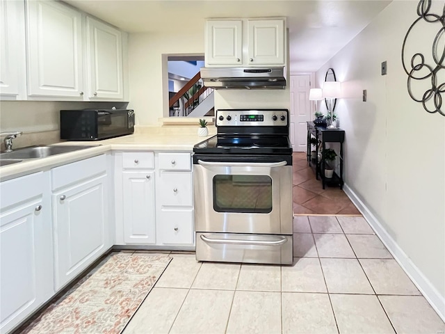 kitchen featuring sink, stainless steel range with electric stovetop, white cabinetry, and light tile patterned floors