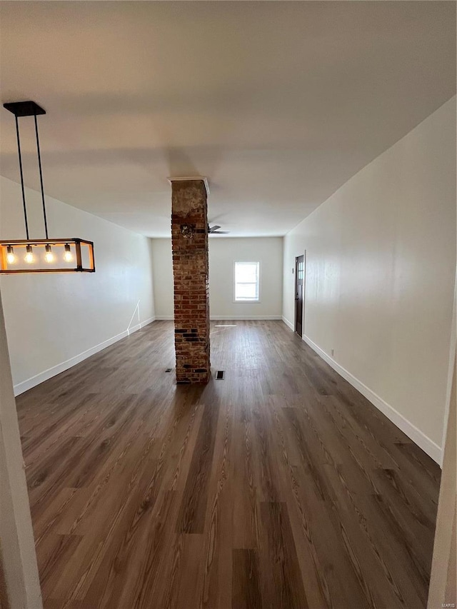 empty room featuring brick wall, dark wood-type flooring, and ceiling fan