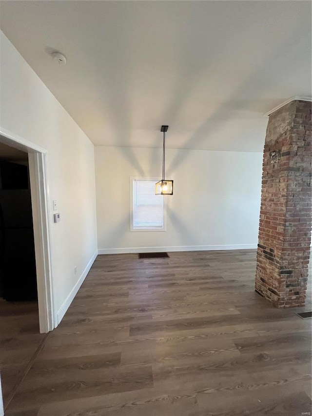 interior space featuring brick wall and dark hardwood / wood-style flooring