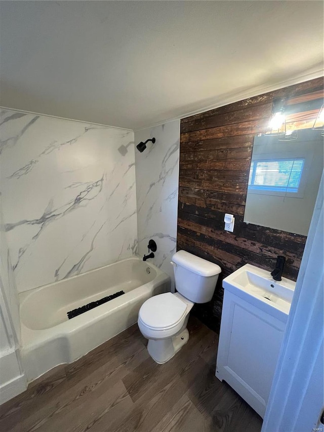 full bathroom with tiled shower / bath combo, toilet, wood walls, vanity, and hardwood / wood-style flooring