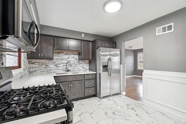 kitchen featuring backsplash, dark brown cabinetry, appliances with stainless steel finishes, light hardwood / wood-style floors, and sink