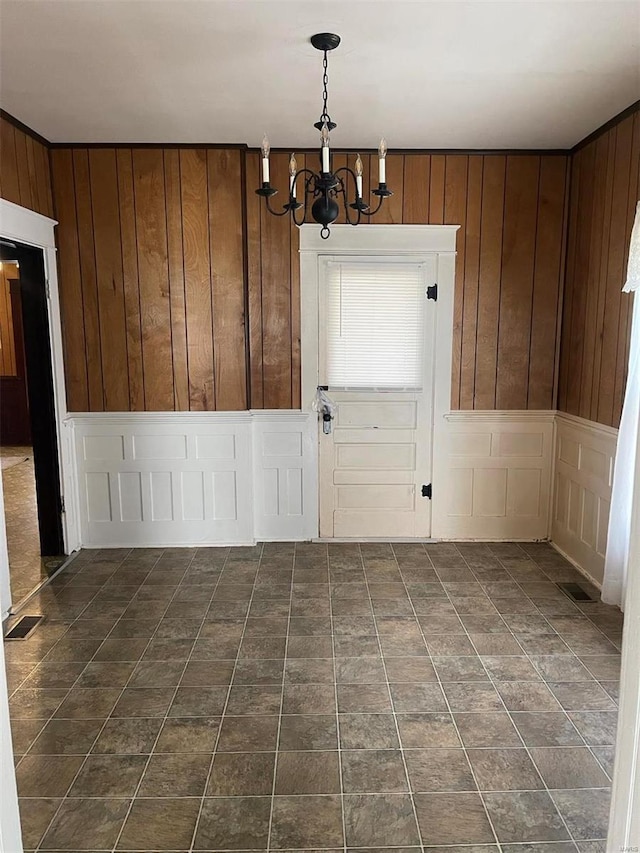 tiled spare room with wood walls and a chandelier