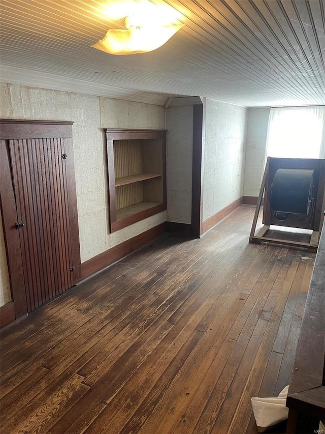 additional living space with built in shelves and dark hardwood / wood-style flooring