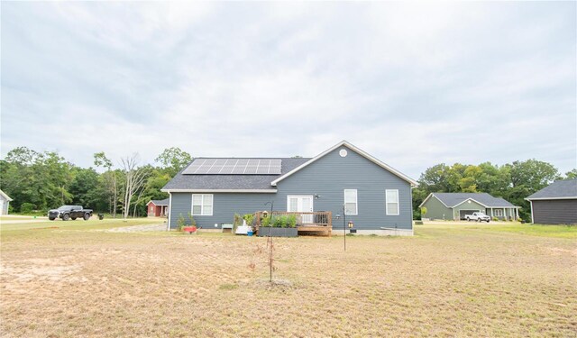 exterior space featuring roof with shingles, a yard, a deck, and solar panels