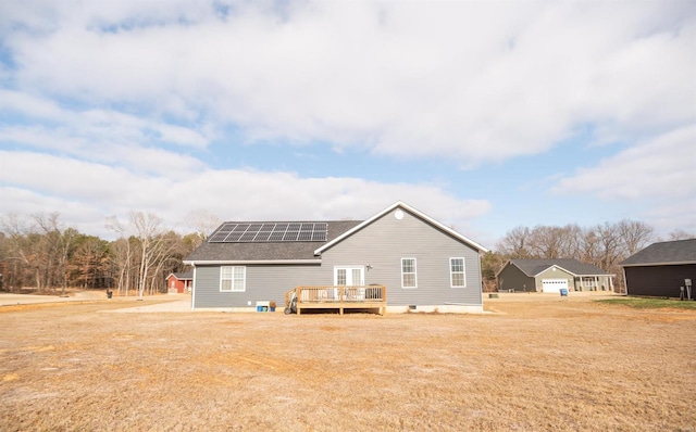 rear view of house featuring a garage, roof mounted solar panels, and a wooden deck