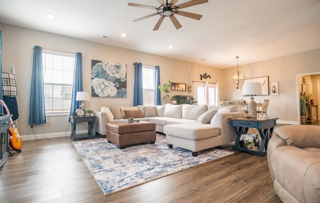 living room featuring dark wood-type flooring and ceiling fan with notable chandelier