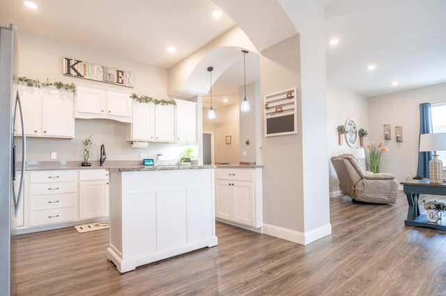 kitchen with hardwood / wood-style flooring, a kitchen island, white cabinets, and hanging light fixtures