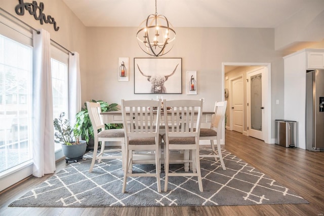 dining area with dark wood-style flooring and an inviting chandelier