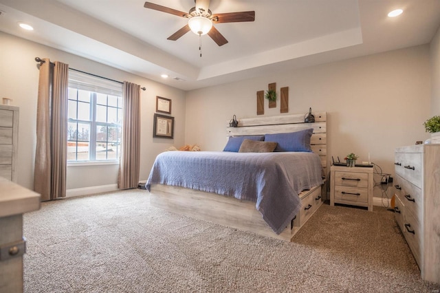 carpeted bedroom featuring baseboards, a tray ceiling, a ceiling fan, and recessed lighting