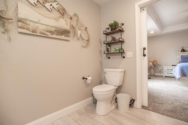 bathroom with ensuite bath, toilet, and baseboards