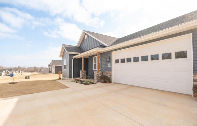 view of front of home featuring driveway, stone siding, an attached garage, and a shingled roof