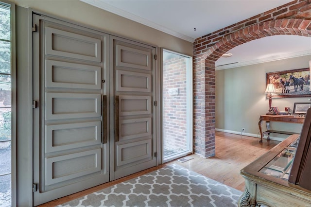 entrance foyer with ornamental molding and light hardwood / wood-style flooring