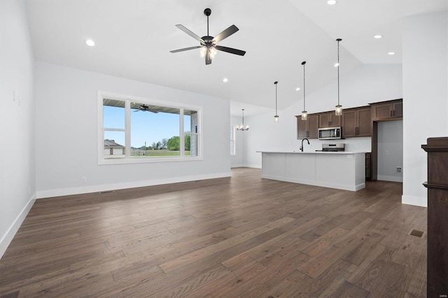 unfurnished living room featuring ceiling fan with notable chandelier, dark hardwood / wood-style floors, sink, and high vaulted ceiling