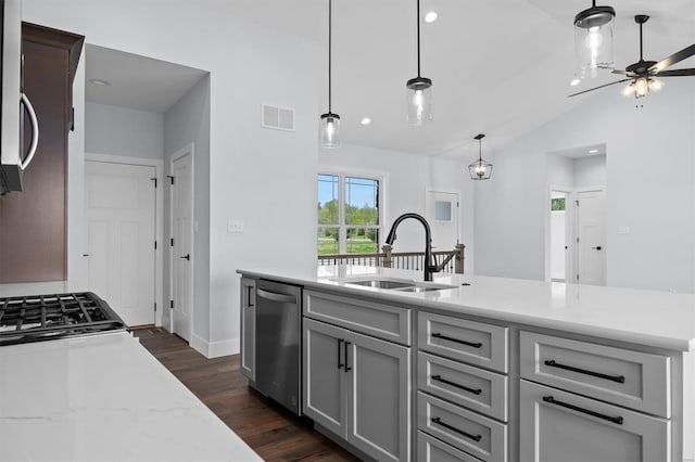 kitchen with sink, appliances with stainless steel finishes, light stone countertops, lofted ceiling, and gray cabinetry