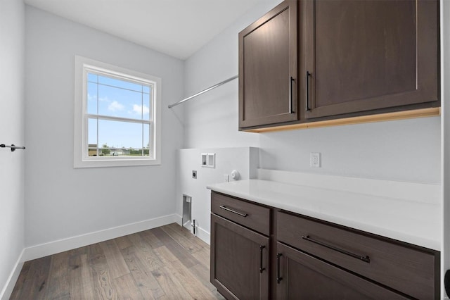 laundry area featuring hookup for a washing machine, light hardwood / wood-style flooring, electric dryer hookup, and cabinets