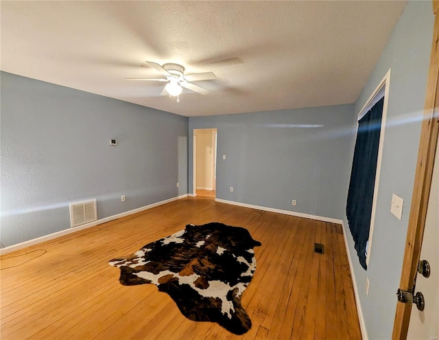 interior space with a textured ceiling, ceiling fan, and light wood-type flooring